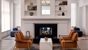 Un salon moderne avec une cheminée, deux canapés, une table basse et des étagères décoratives.