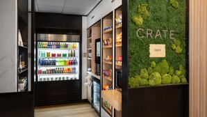 Un bar proposant des collations, doté d’un réfrigérateur pour les boissons, d’étagères remplies de snacks et d’un mur à la texture rappelant la mousse, portant l’inscription « CRATE ».