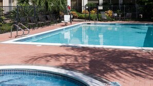 Una piscina con hidromasaje, rodeada de sillas de descanso y un camino de ladrillos.