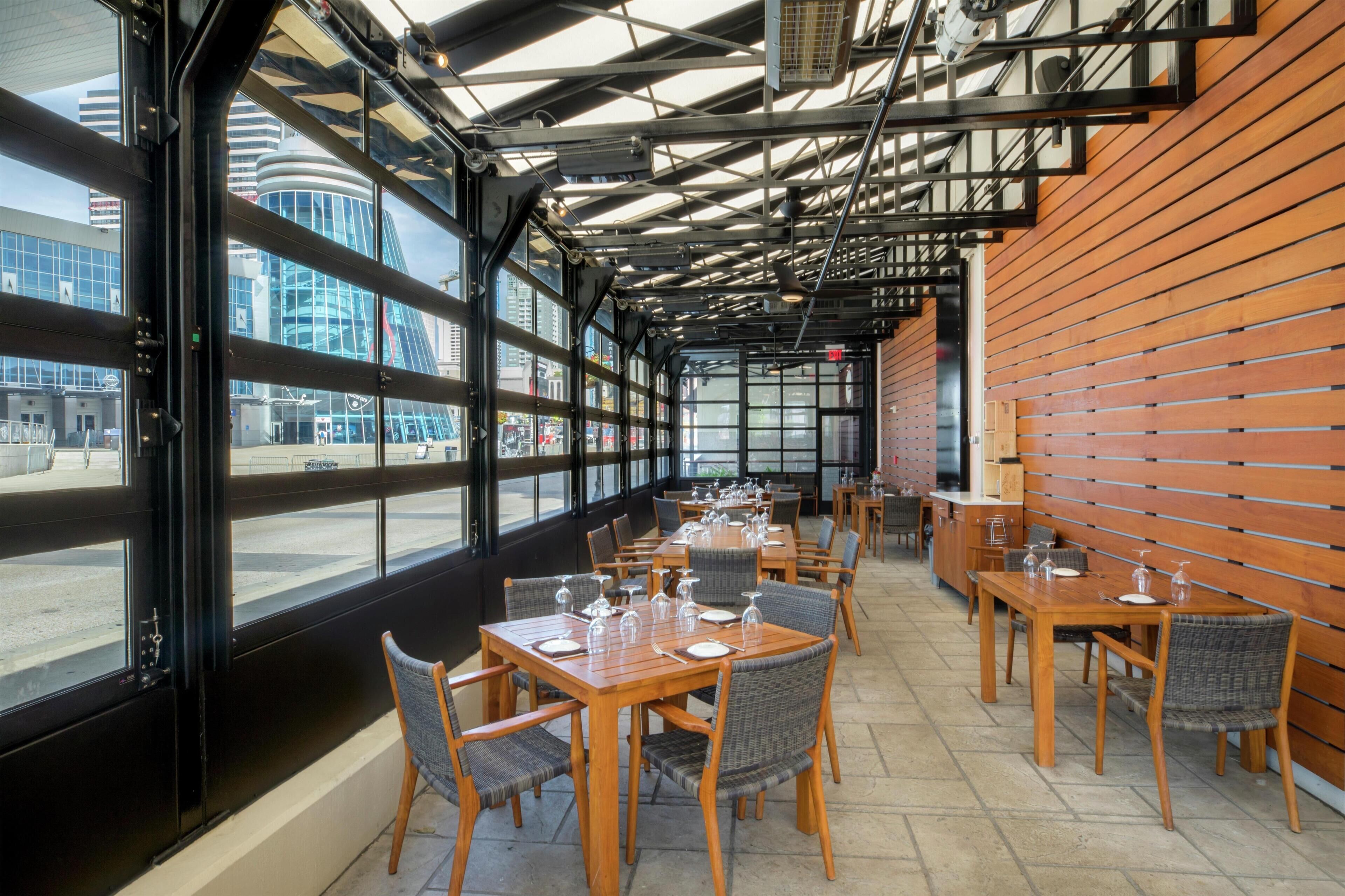 A restaurant with large windows, wooden tables, and chairs.