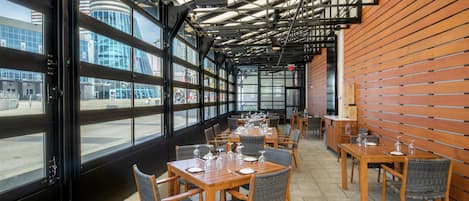 A restaurant with large windows, wooden tables, and chairs.
