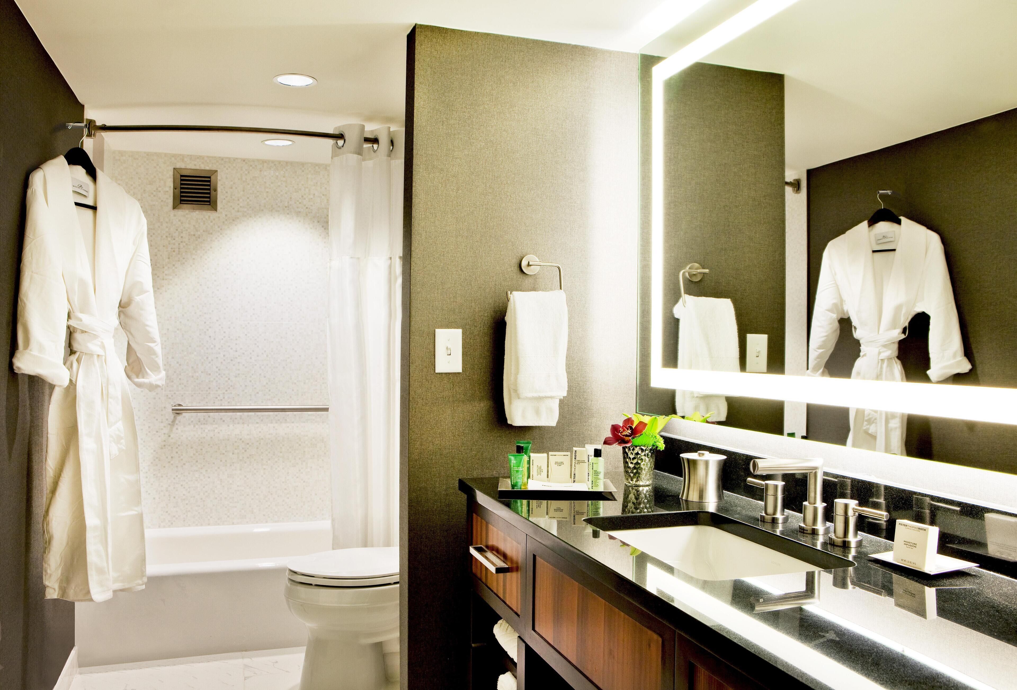 A modern bathroom with a shower, toilet, vanity, and a large mirror.