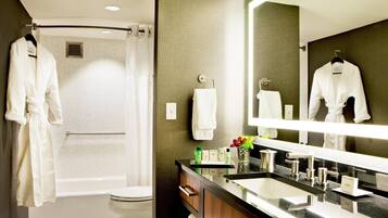 A modern bathroom with a shower, toilet, vanity, and a large mirror.