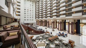 A hotel lobby with multiple floors, a central staircase, and a variety of seating areas including sofas and round tables. - Hilton Nashville Downtown (Nashville)