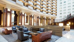 A spacious lobby with multiple seating areas, a reception desk, and a staircase leading to upper floors. - Hilton Nashville Downtown (Nashville)