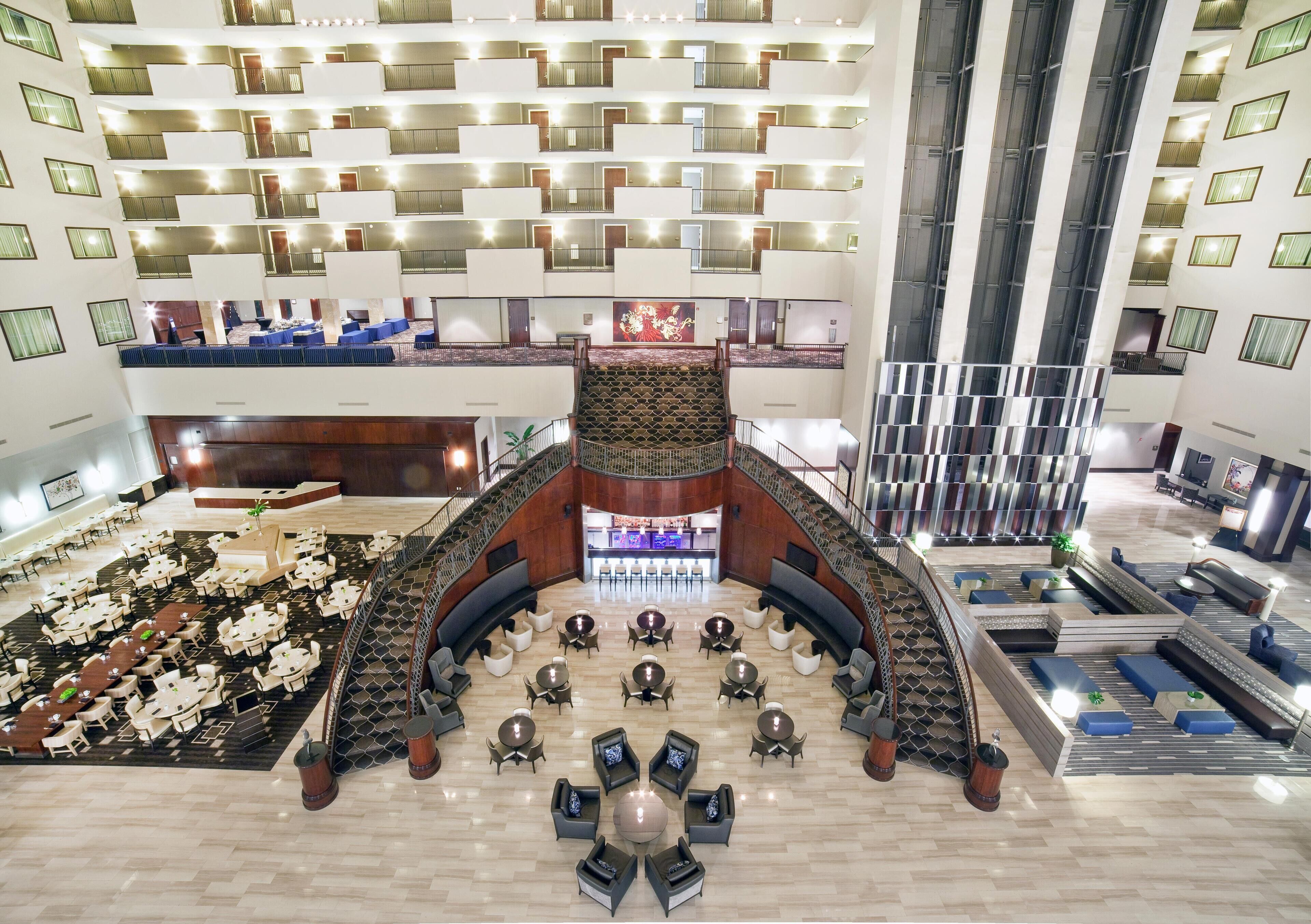 A spacious lobby with multiple seating areas, a central staircase, and a reception desk.