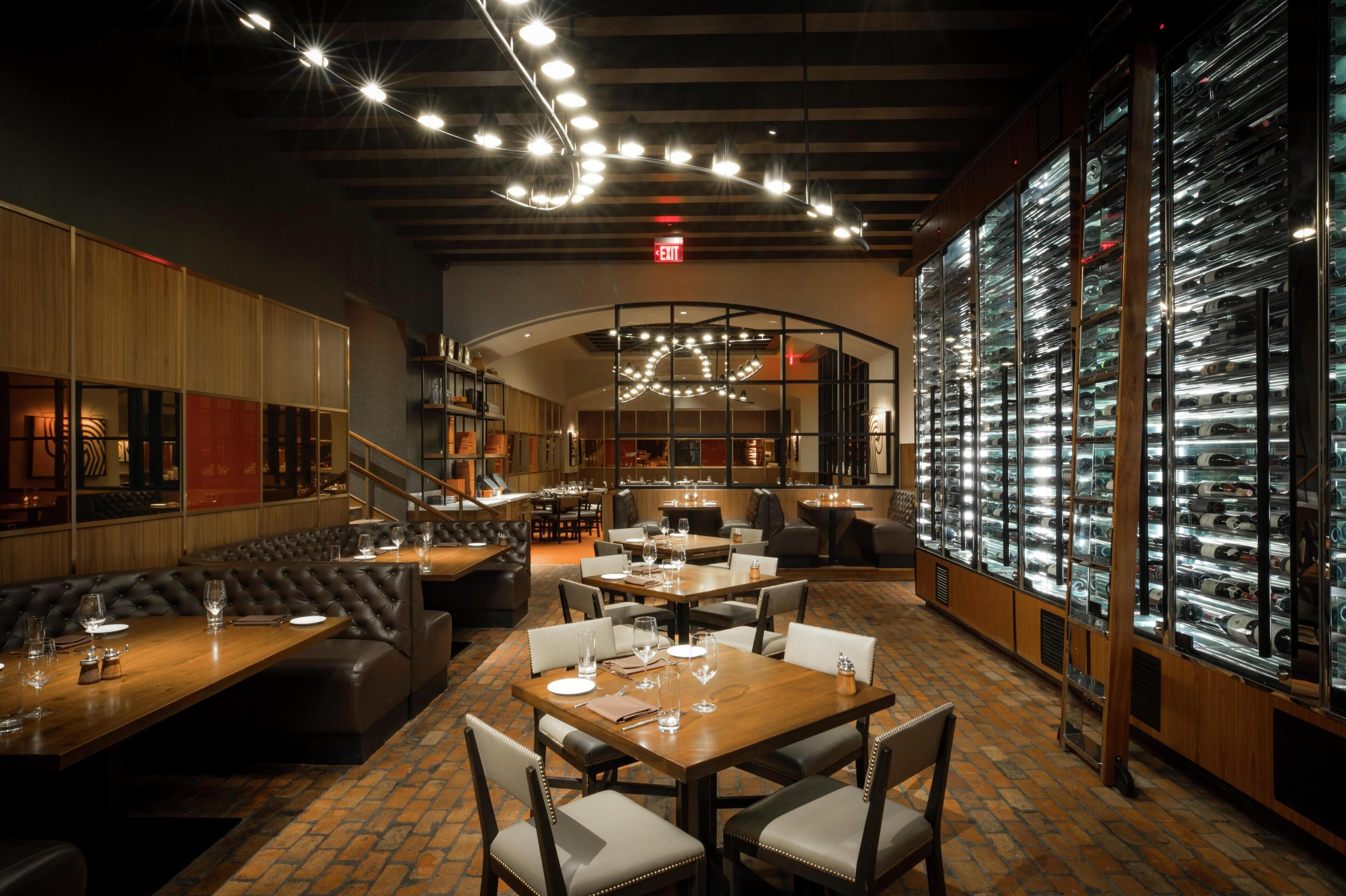 A restaurant with leather booths, wooden tables, and a glass display case of shoes.