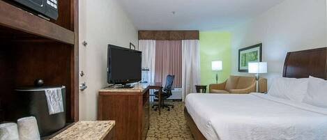 A hotel room with a bed, desk, television, and a chair.
