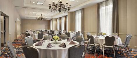 A conference room with round tables, chairs, and a chandelier.