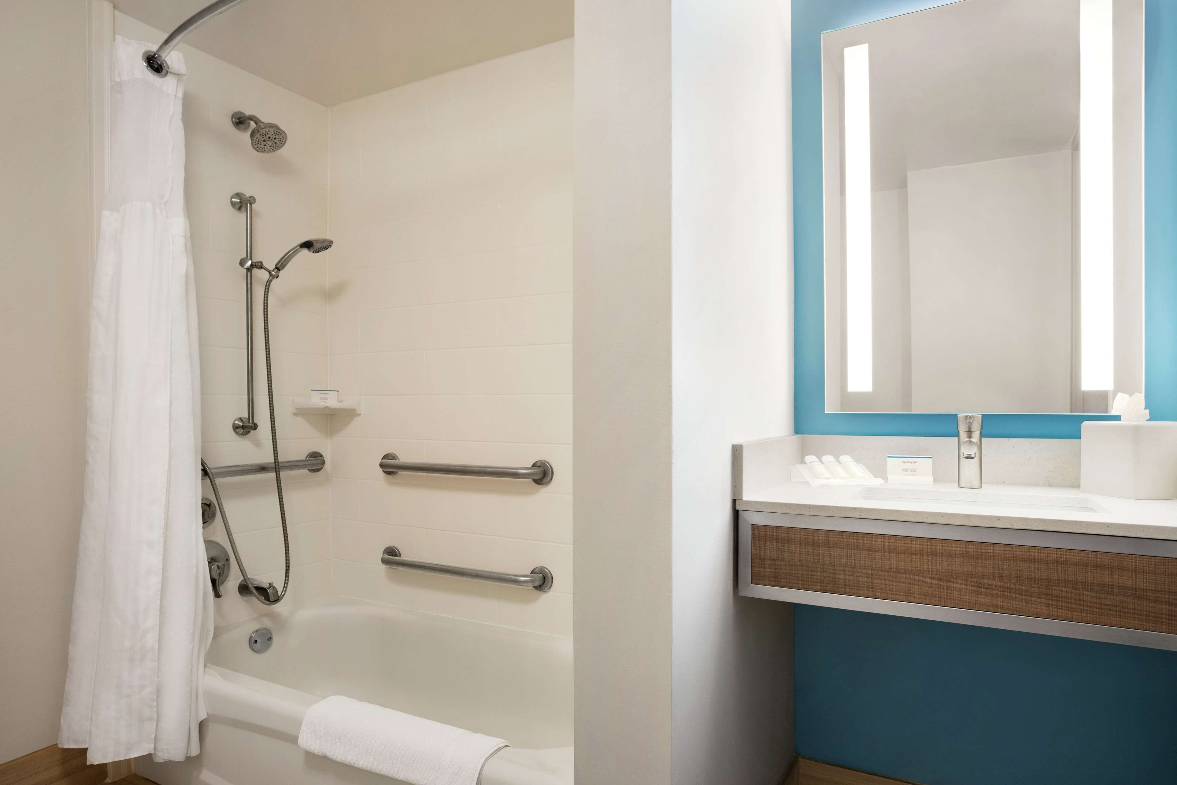 A bathroom with a bathtub, shower, and a vanity with a mirror.