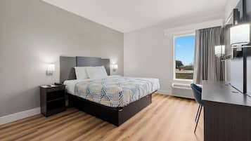 Una camera d'albergo moderna con un letto, comodini, una scrivania e un'ampia finestra con tende.