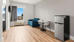 Una cocina moderna con un refrigerador empotrado, una mesa de comedor con sillas y una ventana con cortinas.