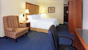 Une chambre d’hôtel avec un lit, une chaise, un bureau et une armoire.