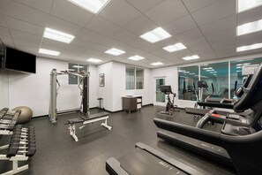 Una palestra con attrezzature per esercizi, un tapis roulant e uno specchio a parete.