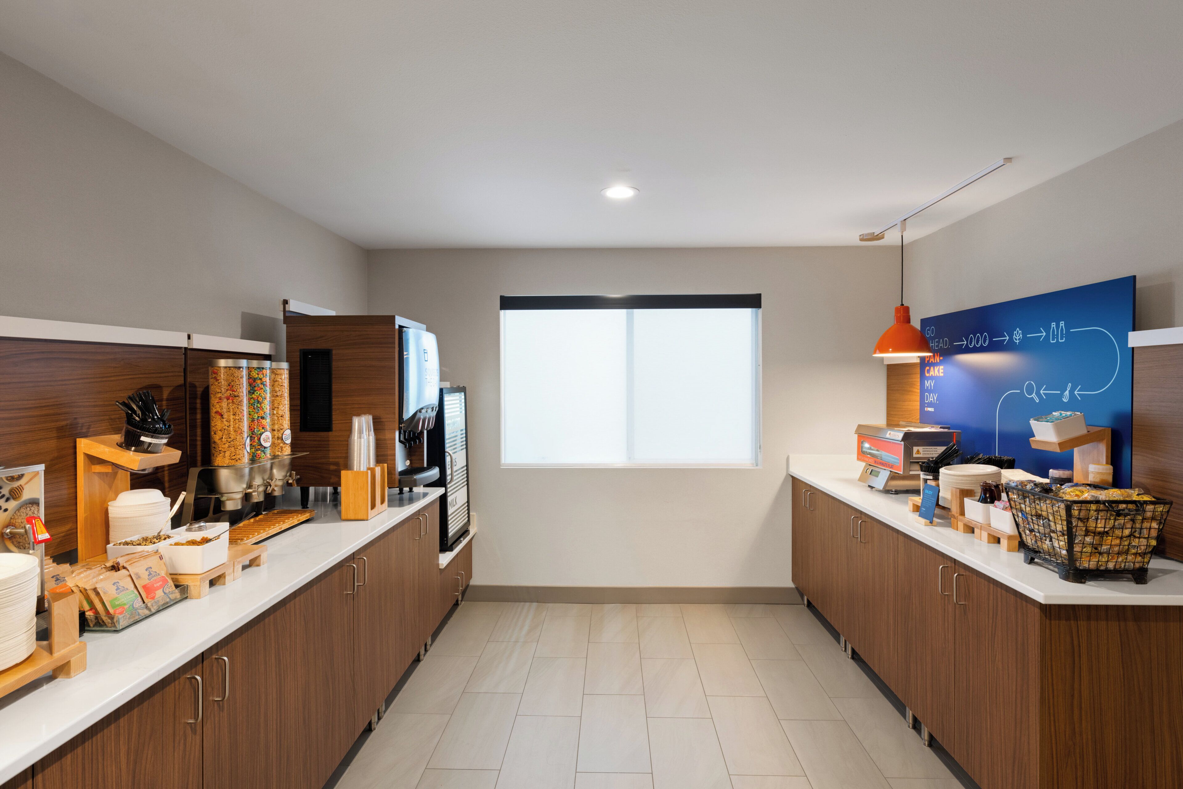 A modern kitchen with a coffee machine, a large window, and a blue informational board.