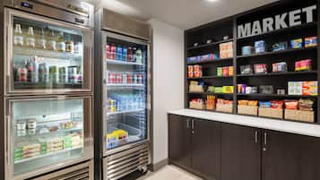 A kitchenette with a refrigerator, freezer, and a pantry stocked with snacks and beverages.
