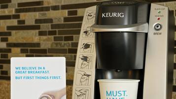 Máquina de café Keurig com uma xícara de café e um anúncio promocional.