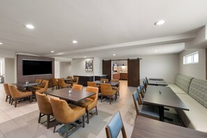 A conference room with multiple tables and chairs, a large flat-screen TV, and a kitchenette area. - Holiday Inn Express & Suites Paso Robles by IHG (Paso Robles)