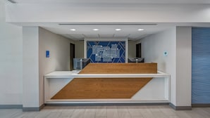 A reception area with a modern design, featuring a reception desk, a blue wall with geometric patterns, and a wooden accent wall. - Holiday Inn Express Hotel & Suites San Diego-Sorrento Valley by IHG (San Diego)