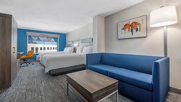 A hotel room with a bed, a blue sofa, a desk, and a chair.