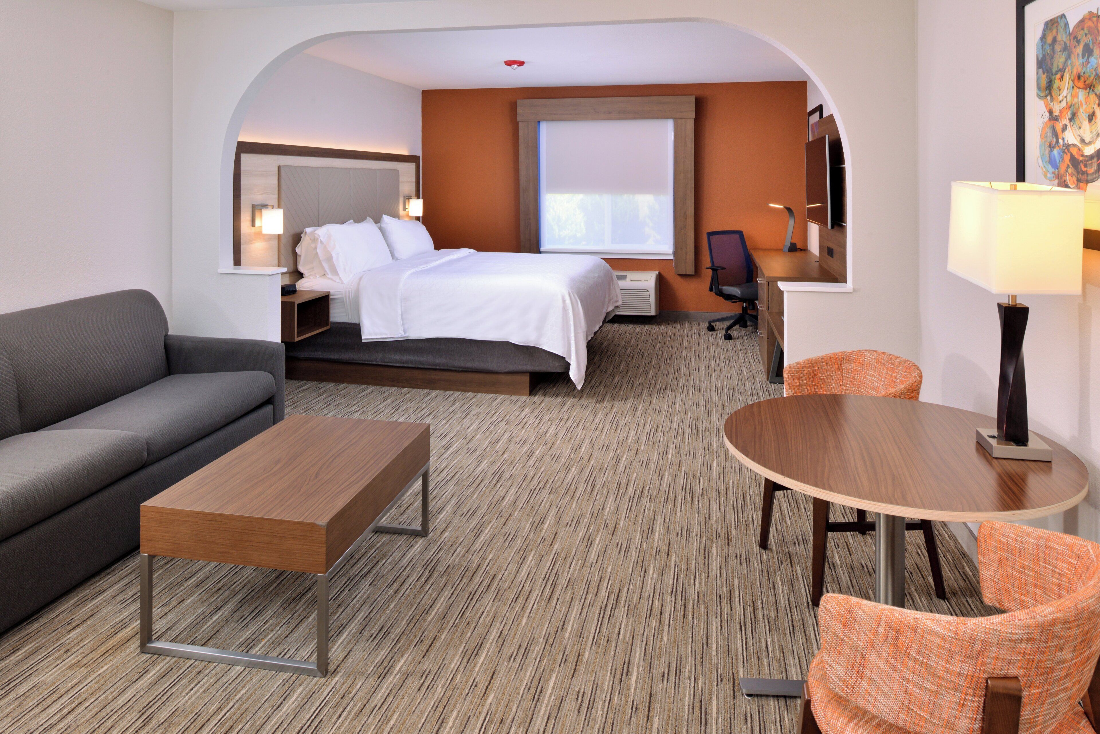 Une chambre d’hôtel avec un lit, un canapé, une table et une chaise.