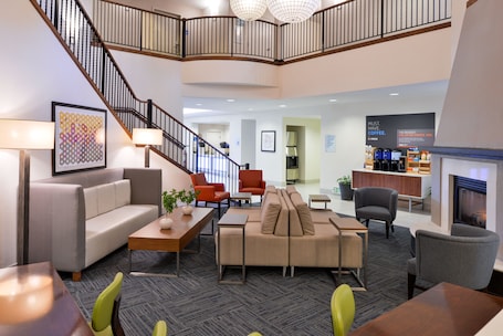 A spacious lobby with a staircase, seating areas, and a coffee station.