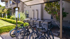 A covered bike parking area with several bicycles, a sign indicating bike rentals, and a building with a modern design in the background. - Holiday Inn Express Arcata / Eureka - Airport Area by IHG (McKinleyville)