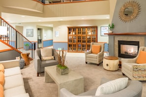 A spacious lobby with a fireplace, seating area, and a staircase.