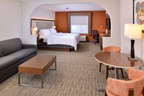 Una habitación de hotel con cama, sofá, una mesita, una mesa redonda y una silla.