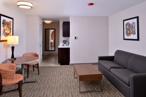 A modern living room with a sofa, a coffee table, and two chairs. There is a kitchen area in the background with a sink and cabinets. - Holiday Inn Express Arcata / Eureka - Airport Area by IHG (McKinleyville)