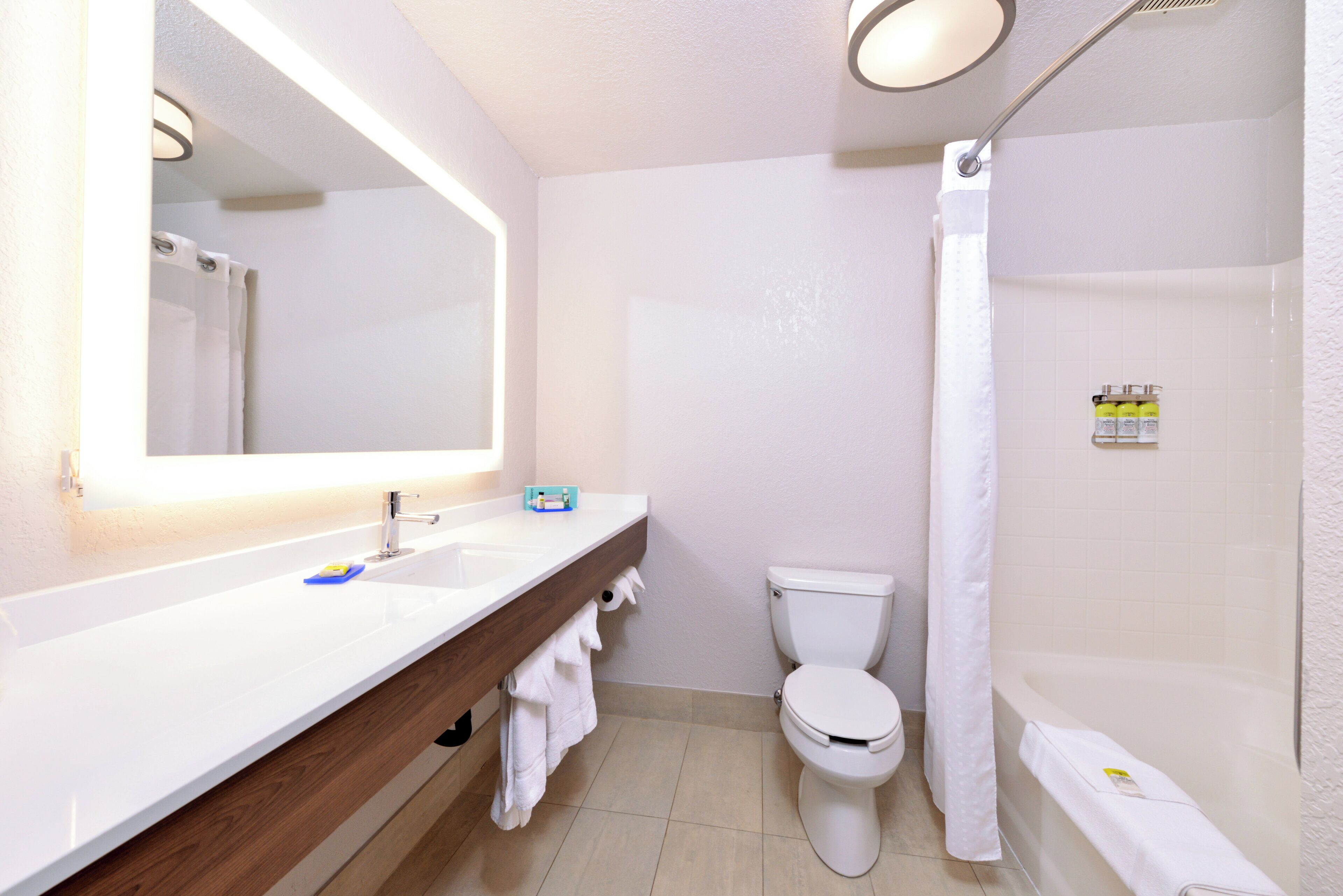 Een badkamer met een wit wastafelmeubel, spiegel en toilet.