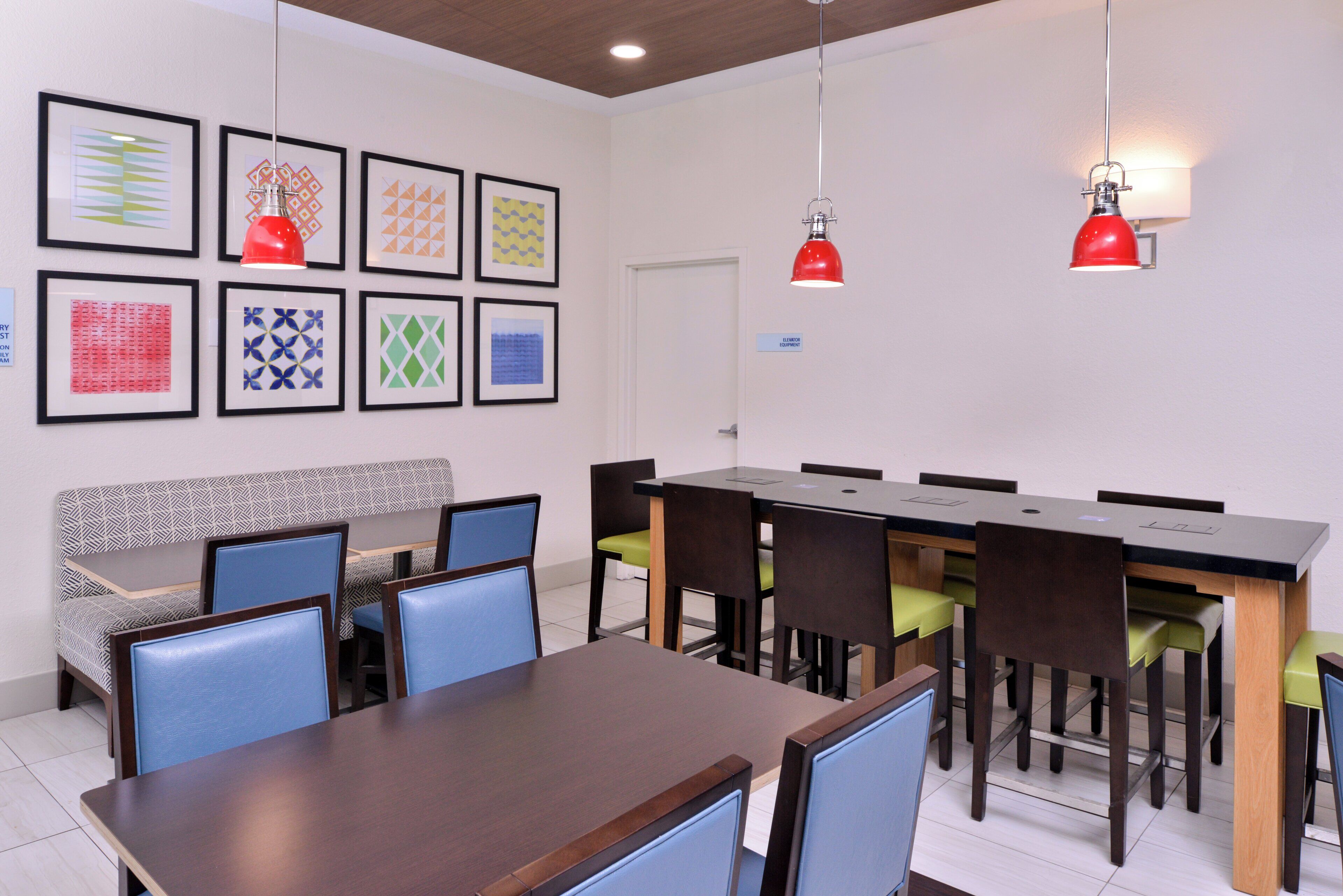 A conference room with a long table, chairs, and framed artwork on the wall.