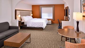 A hotel room with a bed, a sofa, a table, and a TV.