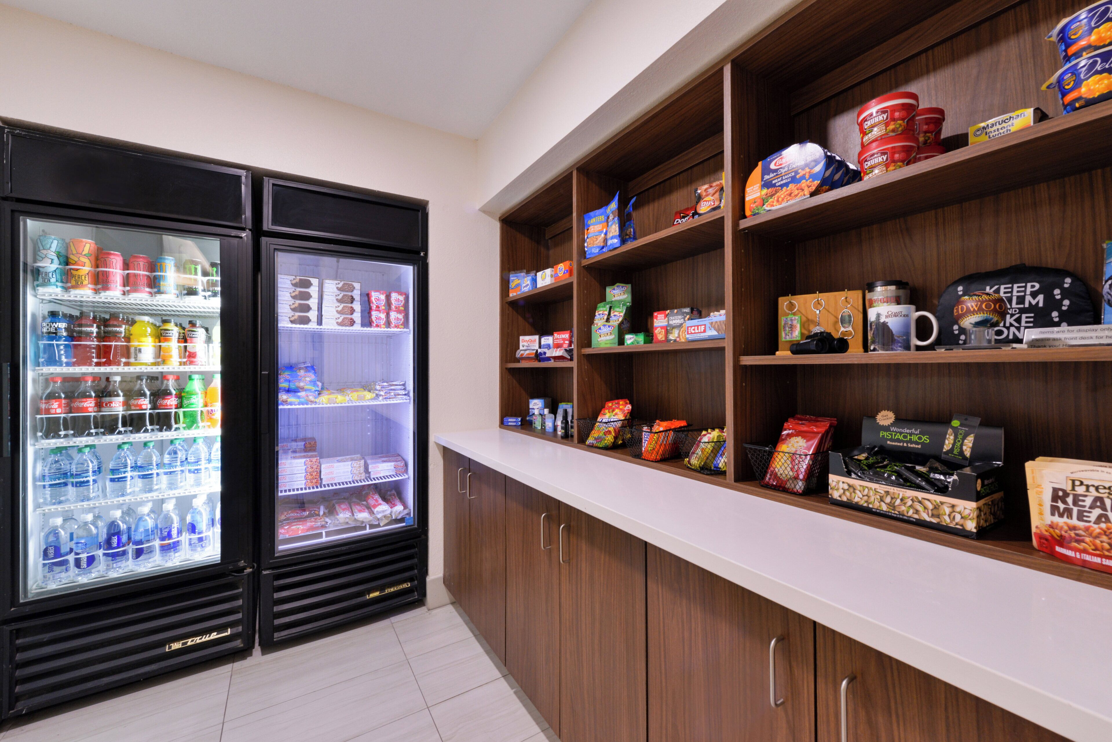A kitchenette with two beverage dispensers, a countertop with various food items, and cabinets.