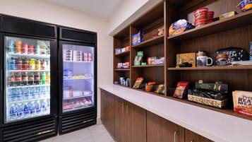 A kitchenette with two beverage dispensers, a countertop with various food items, and cabinets.