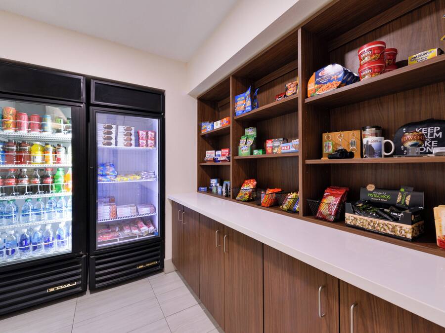 A kitchenette with two beverage dispensers, a countertop with various food items, and cabinets.