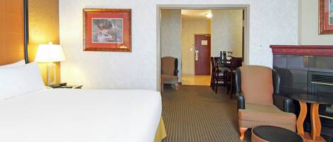 Ett hotellrum med en säng, en tv, en matplats och en hall som leder till ett annat rum.
