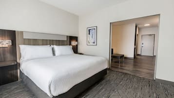 Et moderne hotelværelse med en stor seng, et træpaneleret sengegærde, et natbord med en lampe og et billede i ramme på væggen.
