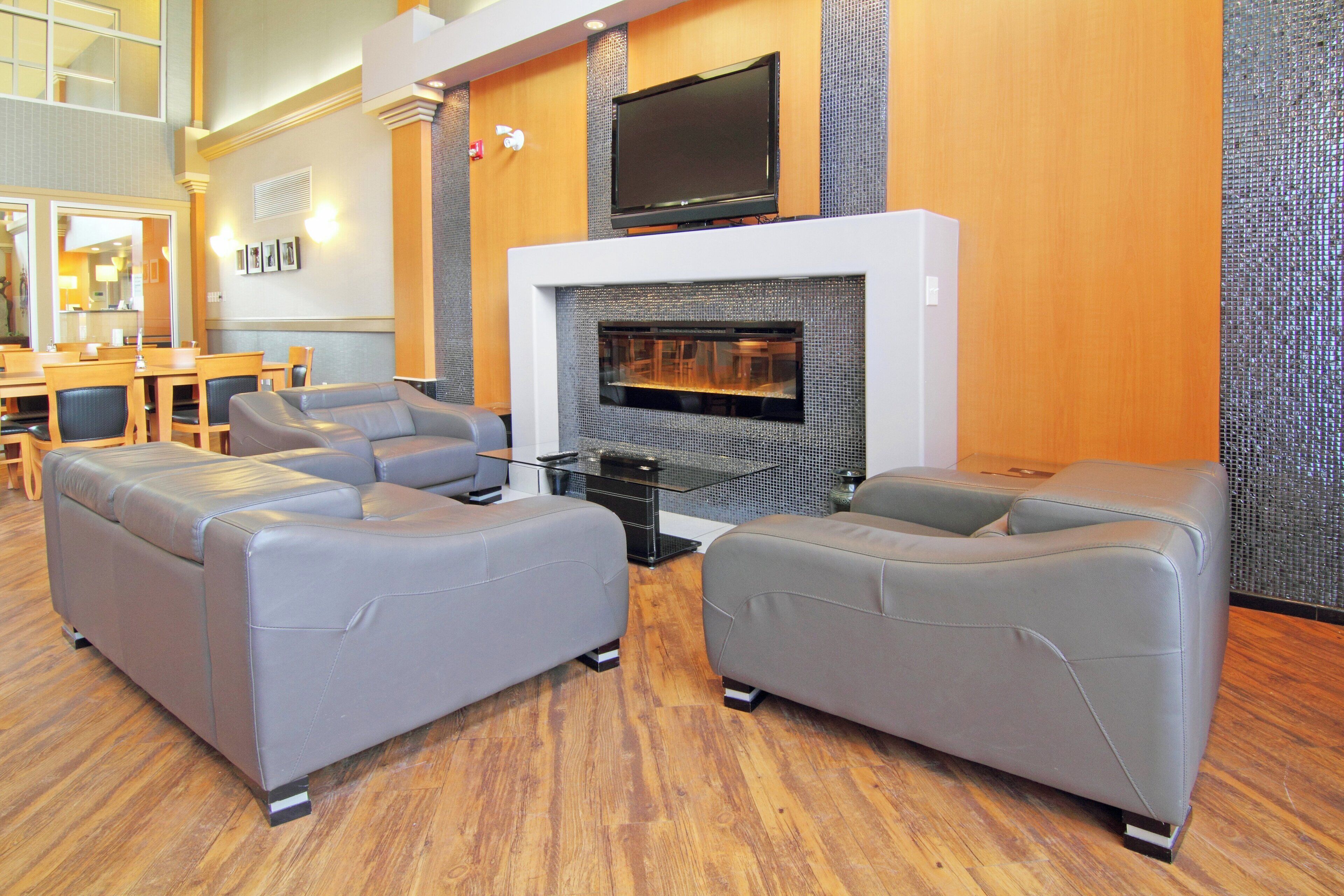 A modern lounge area with leather sofas, a fireplace, and a flat-screen TV mounted above it.