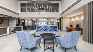 Un'ampia hall con soffitto alto, zona salotto centrale con divano decorato e reception.