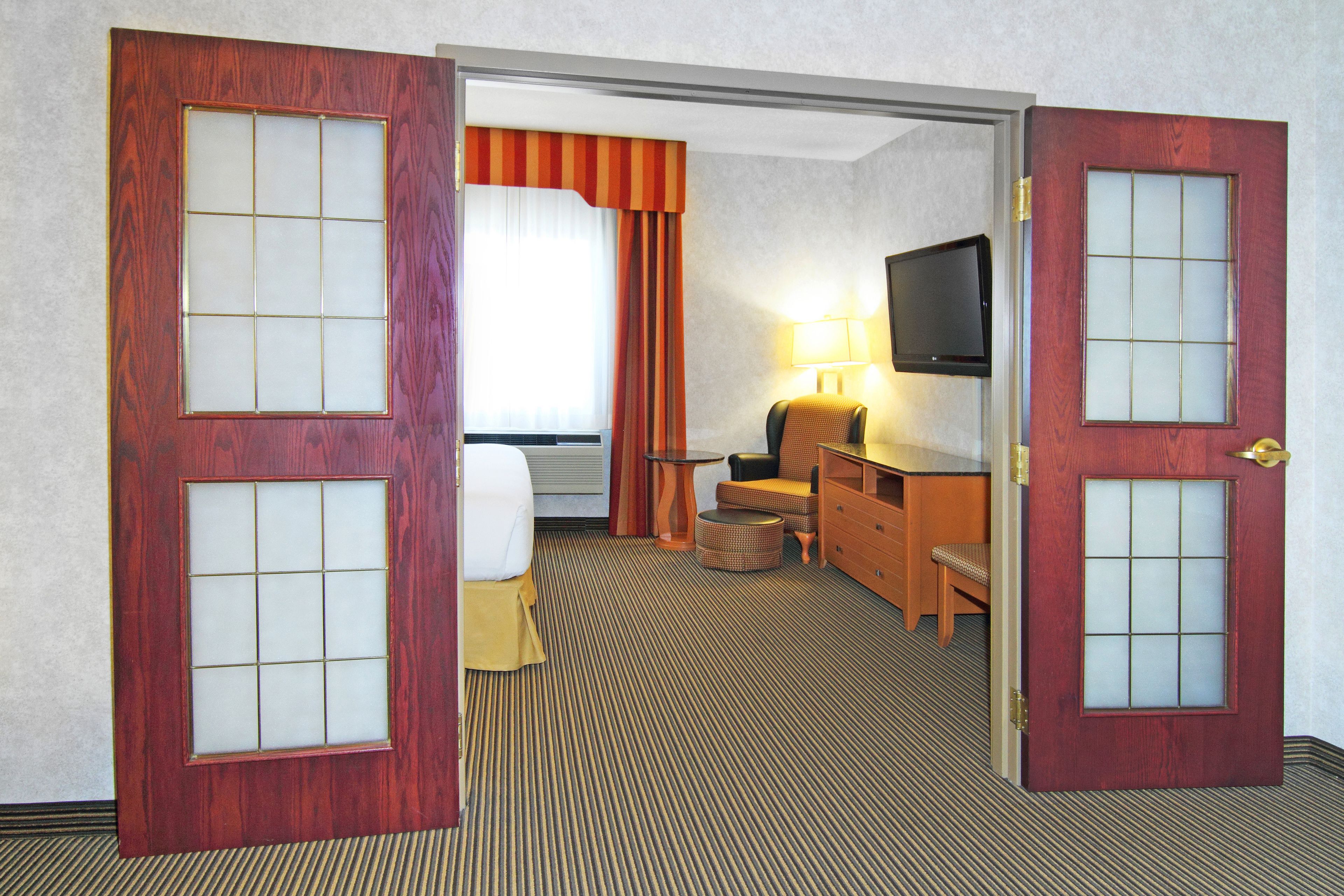 A hotel room with a bed, a desk, a chair, a television, and a window with curtains.