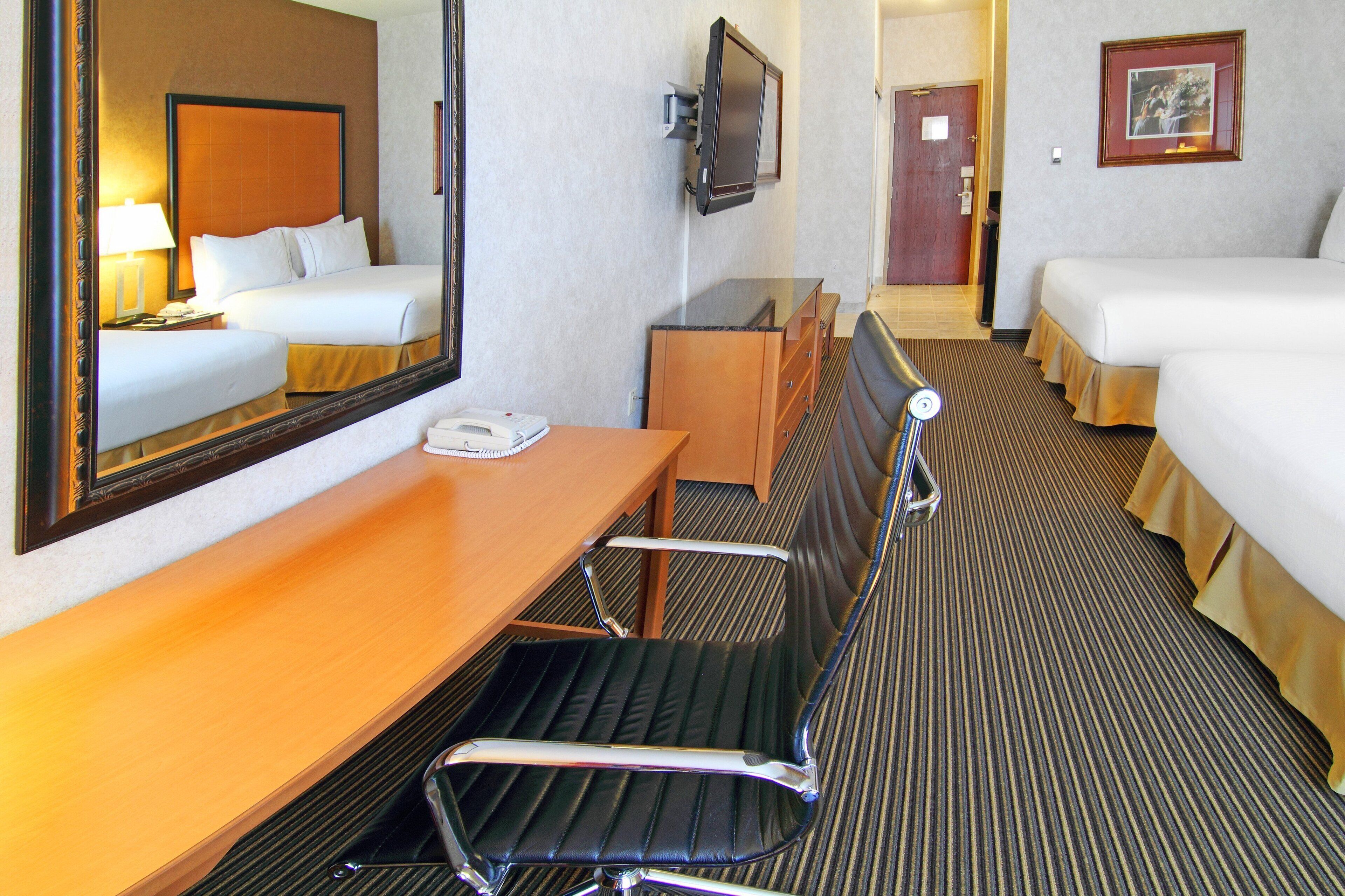 Une chambre d’hôtel équipée d’un lit, d’un bureau, d’une chaise, d’une télévision et d’un miroir.