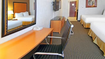 Une chambre d’hôtel équipée d’un lit, d’un bureau, d’une chaise, d’une télévision et d’un miroir.