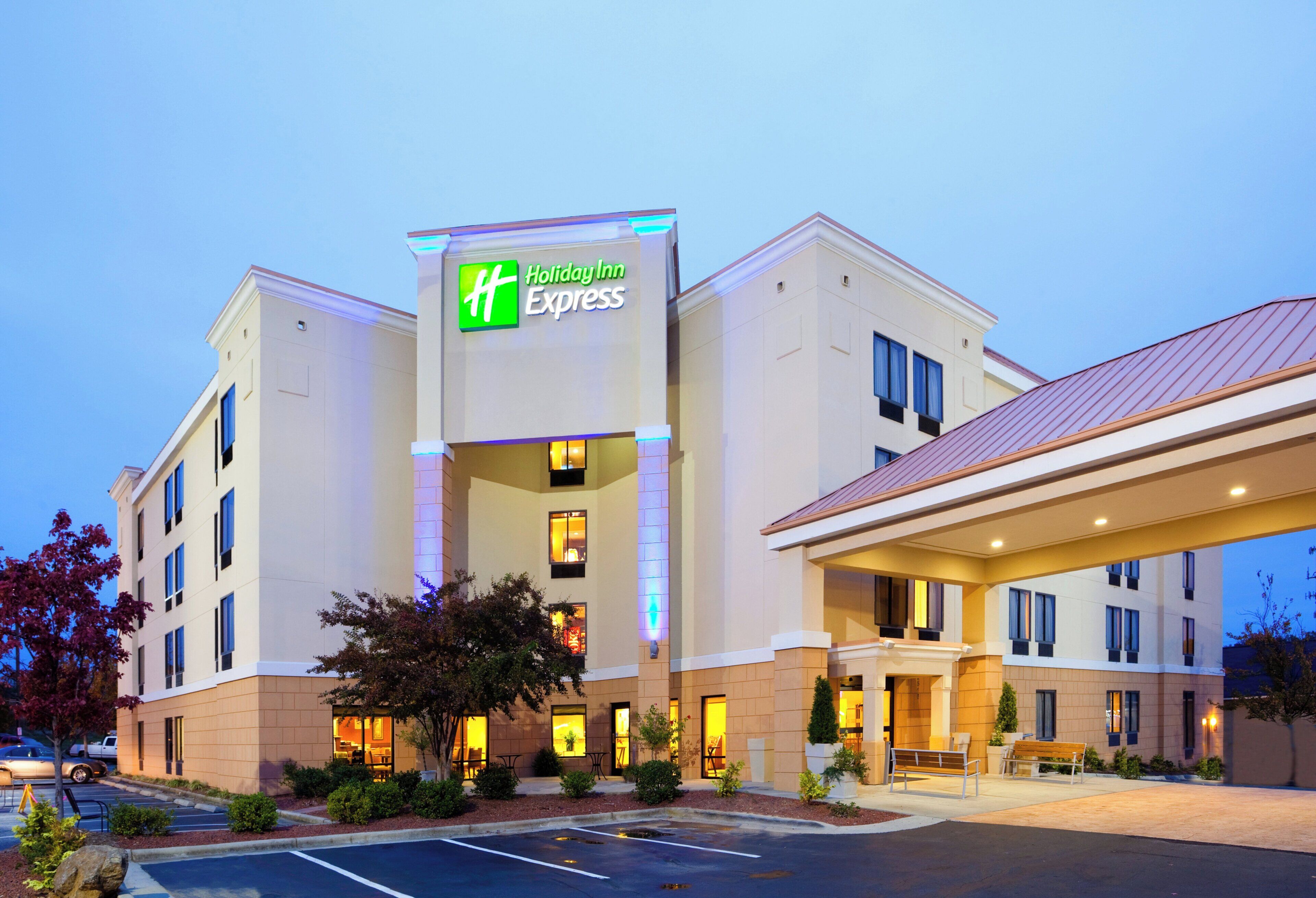 Un hotel Holiday Inn Express con un diseño moderno, que cuenta con un letrero llamativo, varias ventanas y una entrada bien iluminada.