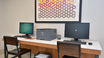 A workspace with two monitors, a printer, and a chair.