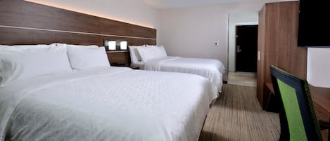 A hotel room with two beds, a flat-screen TV, a wooden headboard, and a carpeted floor.