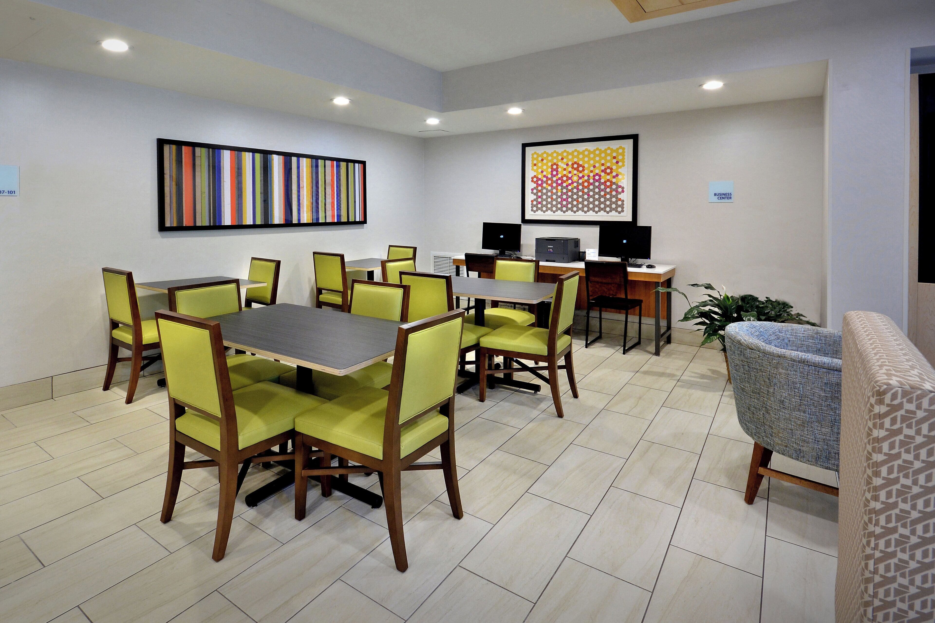 A conference room with a table and chairs, a computer, and artwork on the walls.