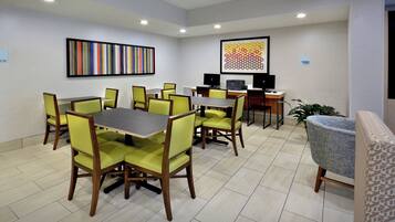 A conference room with a table and chairs, a computer, and artwork on the walls.