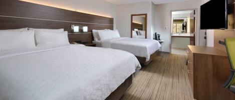 Ett hotellrum med två sängar, en TV, ett skrivbord och en spegel.