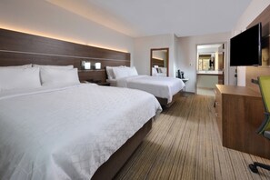 A hotel room with two beds, a TV, a desk, and a mirror.